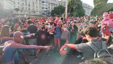 a group of people standing around each other in front of a building with spider man masks on