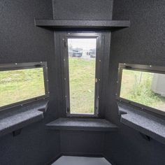 the inside of an rv with two windows on each side and grass in the background