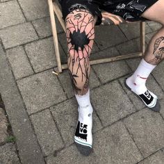 a man sitting in a chair with tattoos on his legs