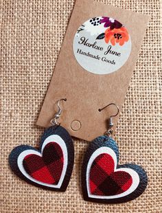 two heart shaped wooden earrings on top of a piece of fabric