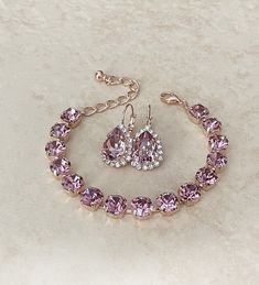 Gorgeous pair of earrings featuring 14x10mm teardrop crystals in a lovely mauve color, surrounded by a halo of sparkling clear rhinestones. Bracelet featuring 8mm round crystals in the same color. Adjustable between 6.5 and 8 inches. Shown in the rose gold metal finish. Pink Crystal Jewelry Sets For Formal Occasions, Formal Rose Gold Teardrop Jewelry, Formal Pink Crystal Jewelry Sets, Pink Jewelry Sets With Sparkling Stones For Wedding, Elegant Purple Jewelry For Wedding, Elegant Lavender Teardrop Jewelry, Pink Sparkling Stones Jewelry For Wedding, Crystal Dangle Jewelry For Bridesmaids, Crystal Dangle Jewelry For Bridesmaid Gift