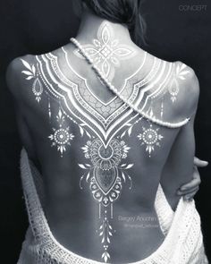 the back of a woman's body covered in white tattoos