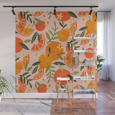 an orange flower painting on a white wall next to a chair and potted plant