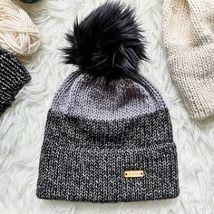 a knitted beanie hat with black fur pom