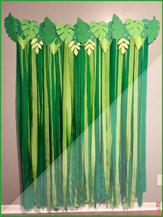 a green curtain with leaves hanging from it's side in front of a wall