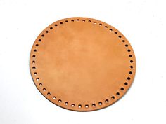 a round leather object with holes in the center on a white surface, top view