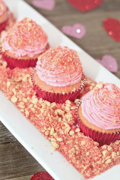 cupcakes with pink frosting and sprinkles on a white plate