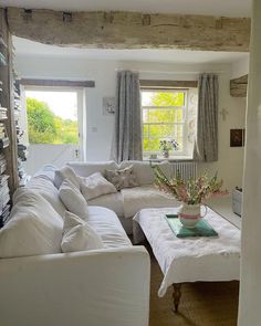 a living room filled with white furniture and lots of windows