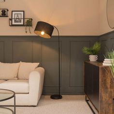 a living room with a couch, table and lamp in front of a wall that has pictures on it