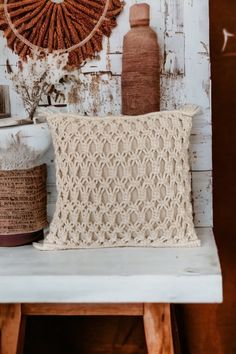 a crocheted pillow sitting on top of a wooden table next to a vase