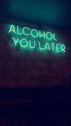 a neon sign that says alcohol you later on the side of a brick building at night