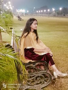 a woman sitting on top of a metal bench