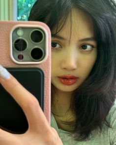 a woman taking a selfie with her cell phone in front of her face and holding it up to the camera