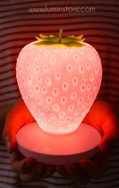 a person holding a lit up strawberry shaped object