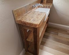 a bathroom sink sitting under a mirror next to a wooden counter and wall mounted faucet