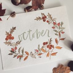 an autumn card with leaves and acorns on it, next to some nuts