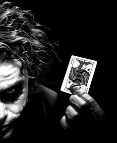 the joker holding up his playing card in front of him with words written on it