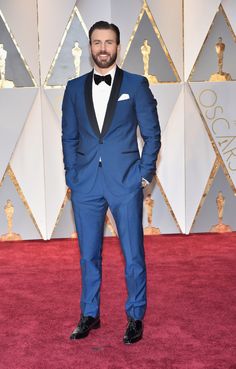 a man in a blue suit and bow tie on the red carpet at an oscars