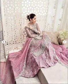 a woman sitting on top of a bench wearing a pink and silver dress with sequins