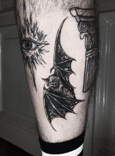 a man's leg with a bat and eye tattoo on it