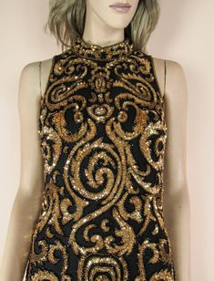 Beaded and sequined dress Hight neckline Back zipper closure It is fully lined with a satin polyester Colour: Black and gold Fabric: Silk chiffon, satin Measurements Bust: 98 cm - 38.6 inches Waist: 80 cm – 31.5 inches Hip: 104 cm - 40.9 inches Length: cm. 100 - 39.4 inches Embellished Sequin Fabric For Cocktail Occasions, Embellished Sequin Fabric For Cocktail Parties, Embellished Sequin Fabric For Cocktail, Elegant Embellished Sequin Fabric For Party, Gold Sleeveless Sequin Fabric For Party Season, Gold Sequin Fabric For Party Season, Glamorous Embellished Sequin Fabric For Evening, Glamorous Fitted Sequin Fabric For Celebration, Black Sequin Fabric For Holiday Party