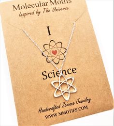 the science necklace is on display in front of a card that says i love it