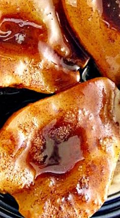 three donuts sitting on top of a black plate covered in caramel glaze