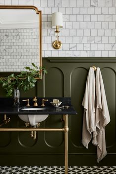 a black and white bathroom with gold fixtures, marble countertops, green walls and brass accents