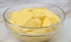 a glass bowl filled with yellow sauce on top of a counter