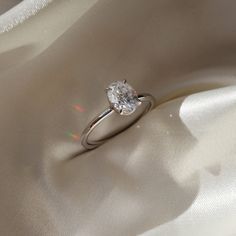 a diamond ring sitting on top of a white satin material covered in light glares