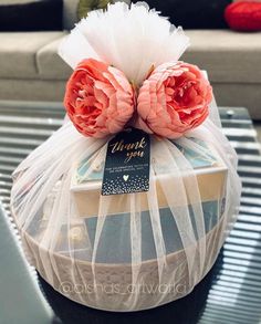 two flowers are wrapped in plastic on top of a coffee table with a thank you tag