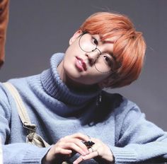 a man with red hair and glasses sitting at a table looking off to the side