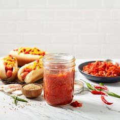 hot dogs and chili sauce in a jar on a table