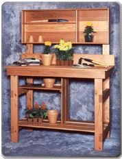 a wooden workbench with potted plants and flowers on the shelf above it