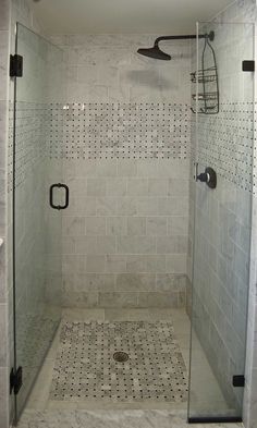 a walk in shower sitting next to a white tiled wall and floor with black accents