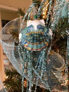 an ornament hanging from the top of a christmas tree with beads and netting