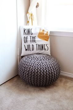 a pillow sitting on top of a cushion next to a white door with the words king of the wild things printed on it