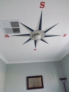 a white ceiling with a black and red compass on it's center piece, in a bedroom