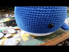 a knitted blue whale hat sitting on top of a wooden table next to shells