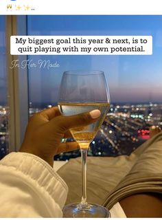 a person holding a wine glass in front of a cityscape with the words, my biggest goal this year & next is to quiting playing with my own potential