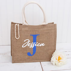 a jute bag with the word jesica on it next to a flower