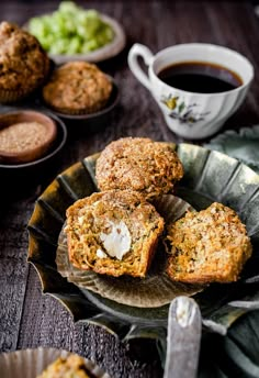 some muffins are on a plate with coffee and other food items around them