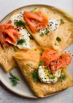 two flatbreads topped with smoked salmon and sour cream sauce on a white plate