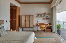 a bedroom with a bed, desk and shelves on the wall next to glass doors