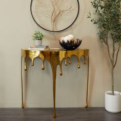 a table with some plants on it in front of a wall and a clock above it