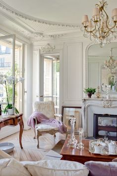 a living room filled with furniture and a chandelier hanging from the ceiling over a fire place