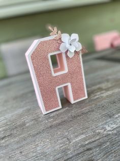 the letter h is made out of glitter and has a flower on it's side