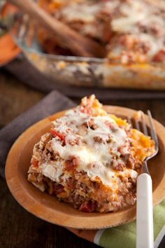 a slice of lasagna casserole on a wooden plate with a fork