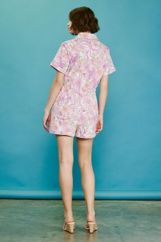 A playful take on effortless dressing, this short-sleeve twill romper showcases a retro-inspired floral print in a pastel color palette. It buttons at the front and features a pointed collar, patch pockets, and an elasticized waist to define the shape. •Short sleeves •Pointed collar •Button placket •Patch pockets •Elasticized waist Item Number: 74402