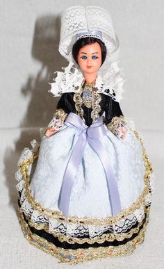 the doll is wearing a blue dress and white hat